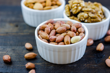 Fototapeta na wymiar Tasty nuts arrangement in a bowl on a wooden table. Healthy food and snack, organic vegetarian food. Walnut, almond, peanut