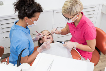 Zahnärztin und Assistentin bei der Untersuchung der Zähne eines Mädchens