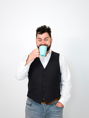 handsome, young man with black beard posing with turquoise coffee cup or tea cup in front of white background and making different facial expressions