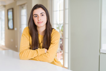 Beautiful young woman wearing yellow sweater with serious expression on face. Simple and natural looking at the camera.