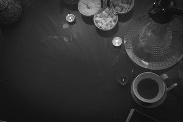 Obraz premium Hookah on glass table top view. cups candle and smartphone eastern tea ceremony. Selective focus, sugar cubes with different flavors. Copy space, black and white