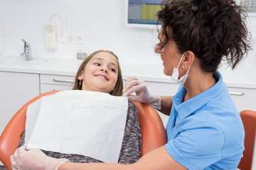 Mädchen bei Zahnarztbesuch lächelnd auf dem Behandlungsstuhl