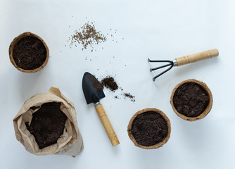 Eco friendly pots for seedlings and seeds on white background, small bag with ground and garden...