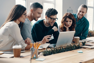 Another working day. Group of young modern people in smart casual wear using modern technologies...