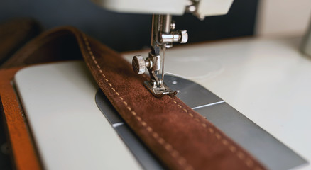 Background type of sewing machine, leather belt sewing process. Leather workshop.