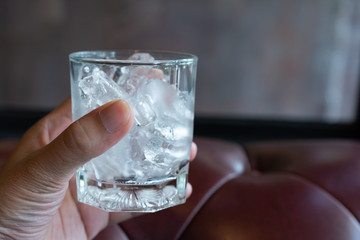 Ice cube in the glass with sofa wallpaper.