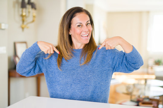 Beautiful middle age woman at home looking confident with smile on face, pointing oneself with fingers proud and happy.