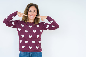 Beautiful middle age woman wearing heart sweater over isolated background smiling confident showing and pointing with fingers teeth and mouth. Health concept.
