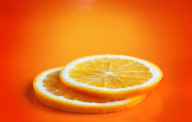 two orange slices on bright orange background with copy space