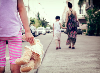 Child with Plush Doll Abandoned as Mother and Another Child Walks Away.