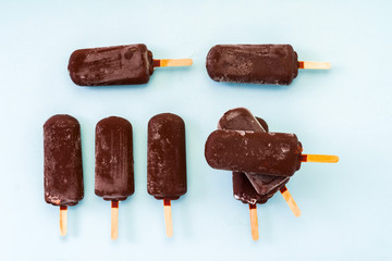 chocolate popsicle ice cream on a wooden stick on a light blue background
