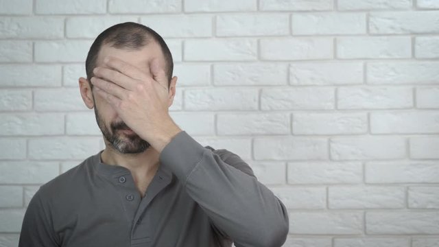 The man is disappointed. Frustrated man covers his face with his palm.