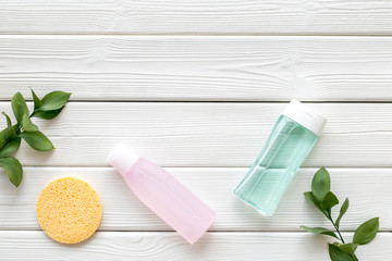 skin care cosmetics with facial tonic, mycelial water and sponge on white wooden background top view mockup