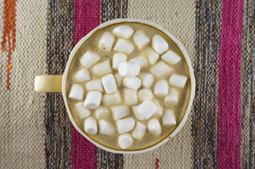 Nice Cup of coffee with marshmallow. Striped fabric background. Flat lay.