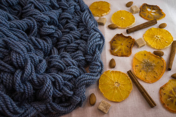 A white background with a blue knitted blanket in a cozy style. Slices of dried orange, persimmons and almonds.