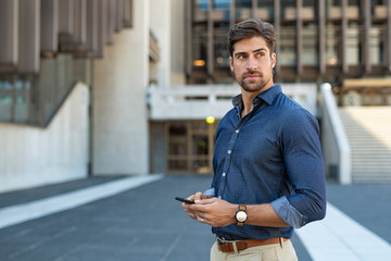 Thoughtful young businessman holding phone