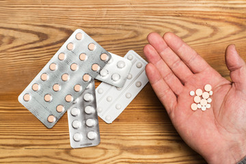 Mano de hombre abierta con medicamentos pastillas junto a unos blister. Vista superior. Concepto:...