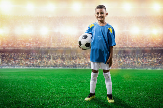 Asian Soccer Kids Player In Blue Jersey Standing And Pose To Camera In The Stadium