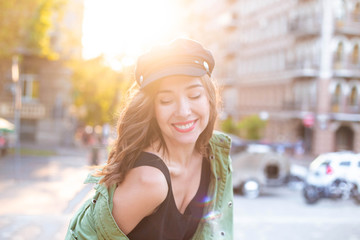 Beautiful sexy tourist girl walking in summer city street with curly hair flying on the wind. Woman looking at camera outdoors wearing fashionable clothes. Copy space.Close-up Fashion woman 