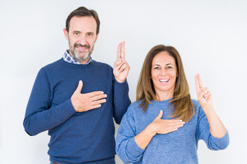 Beautiful middle age couple in love over isolated background Swearing with hand on chest and...