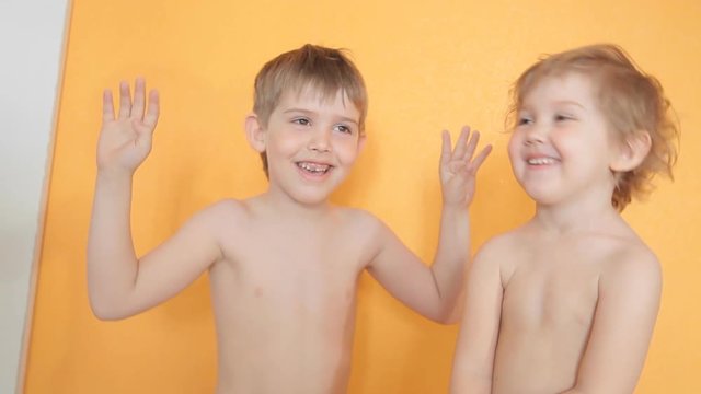 little brother and sister hug and kiss each other, grimace, and laugh happy dance