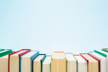 Row of old books with colorful covers on pastel blue background. Education concept. Mock up for...