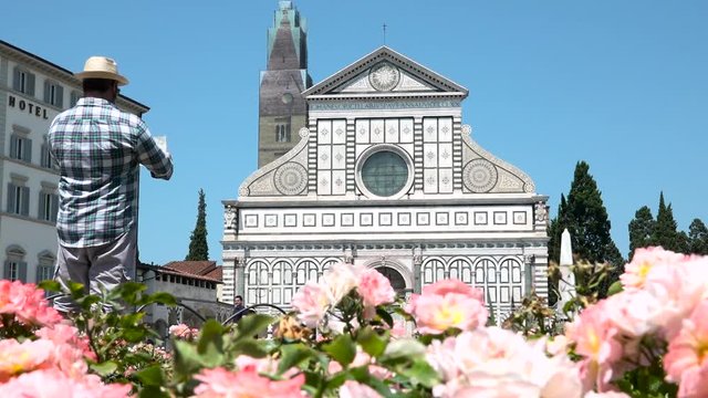 Smiling tourist with city map visiting Santa Maria Novella church, Florence, Italy. Happy man travels to best place of Tuscany, boy visiting buildings. Must see sightseeing of Firenze, Italian tour