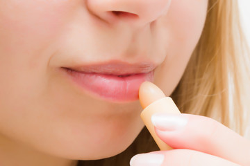 Young woman using natural lips balm on light gray background. Care about healthy, moisture and soft...