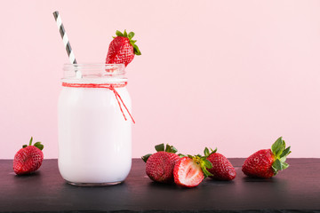 Strawberry milkshake with berry in mason jar on pink. Close up. Summer drink.