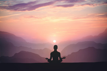 Man practices yoga and meditates on the mountain.