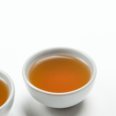 A small cup with brewed green tea on a white background. Minimal composition. Concept useful refreshing natural diet drink