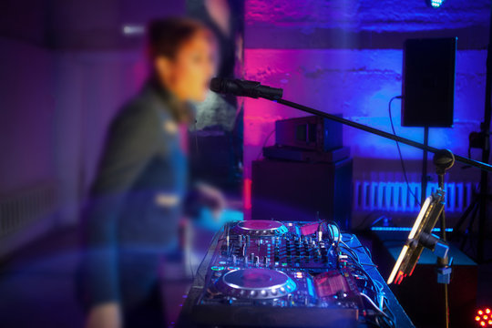 Pretty Dj girl playing songs in a disco with light show
