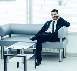 successful businessman sits in the lobby of a modern office and