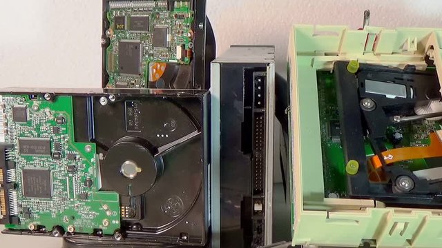 Stack of old SATA, ATA hard disk drives and driver cd disassembled.