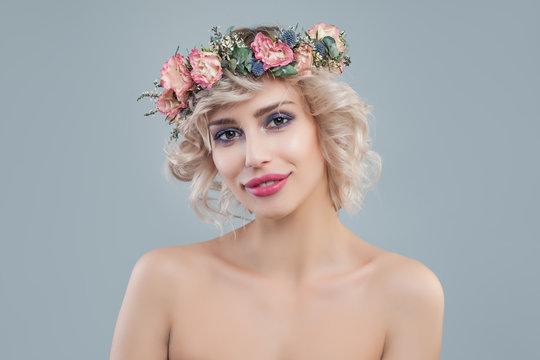 Fashion model with flowers. Cheerful blonde woman with short haircut and makeup on blue background