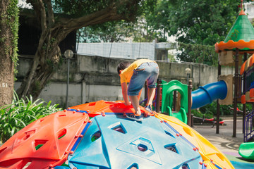 Asian kid boy having fun to play on children"s climbing toy at school playground, back to school outdoor activity.