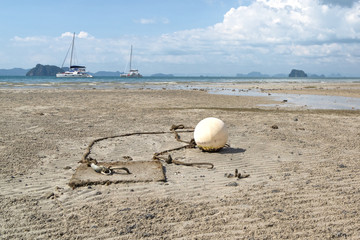 Fototapeta na wymiar White round floating buoy on the seabed in the morning low tide.