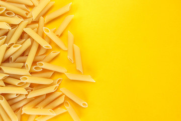dry pasta penne Italian food yellow background.