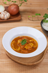 Tasty dinner with chicken curry in bowl on wooden background