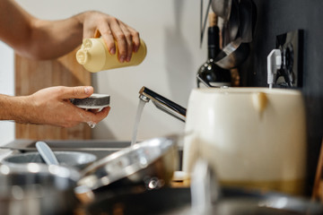 Homework, male hands with a sponge and special.  detergent for oily weeds in the kitchen.