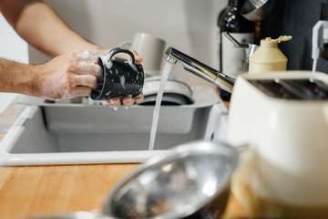 Homework, male hands with a sponge in the foam wash a gray mug in the sink in the kitchen.