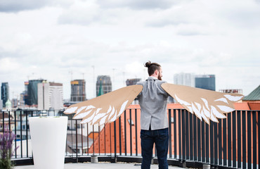 A young businessman with wings standing on a terrace, flying metaphor concept.