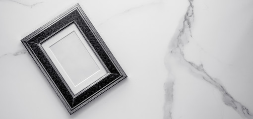 Black photo frame on marble, flatlay