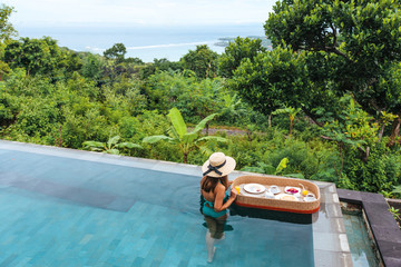 Girl eating floating breakfast in luxury infinity pool