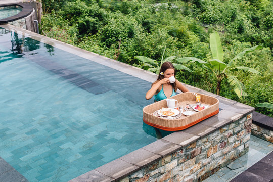Girl eating floating breakfast in luxury hotel pool