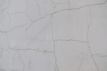 A crack in the concrete wall. Textured stone gray wall. Peeling paint on the cement surface.