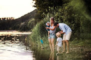 A young family with two toddler children outdoors by the river in summer.