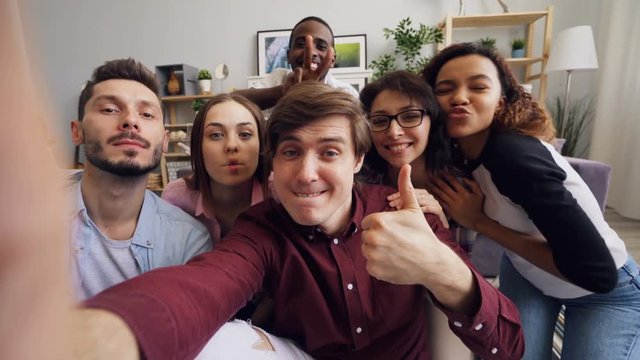 POV of joyful young people friends taking selfie with funny faces and hand gestures looking at camera smiling having fun. Modern technology and friendship concept.