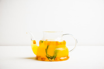 Hot buckthorn beverage in glass teapot. Selective focus. Shallow depth of field. 
