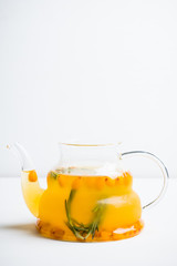 Hot buckthorn beverage in glass teapot. Selective focus. Shallow depth of field. 